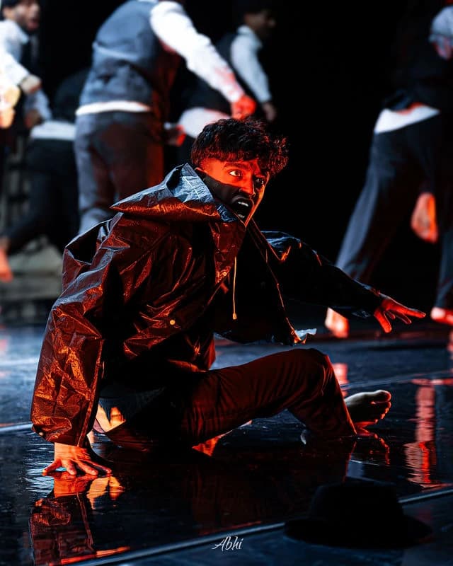 An NDDL dancer holding a powerful floor pose under warm red light